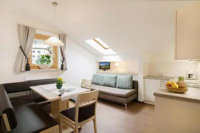a kitchen and living room with a table and a couch at Hotel Schönbrunn in Schenna