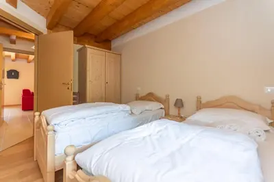 two beds in a room with wooden ceilings at Residence Rosental in Alleghe