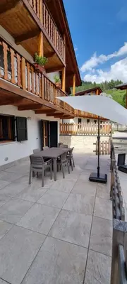 a patio with a table and benches in front of a building at Residence Rosental in Alleghe