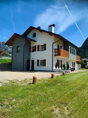 a large white house with a grassy field in front at appartamento PANORAMA in Pozza di Fassa