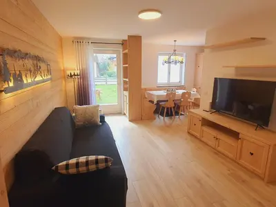 a living room with a couch and a flat screen tv at Cuore delle Dolomiti - Alpine Stay Apartments in Ziano di Fiemme
