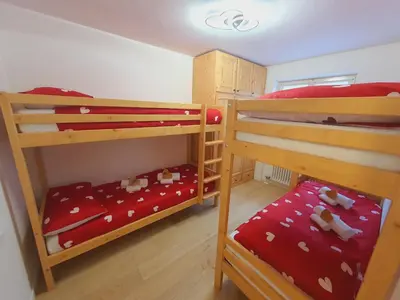 a bedroom with two bunk beds with red sheets at Cuore delle Dolomiti - Alpine Stay Apartments in Ziano di Fiemme