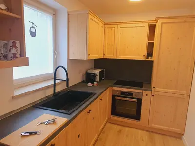 a kitchen with wooden cabinets and a sink and a window at Cuore delle Dolomiti - Alpine Stay Apartments in Ziano di Fiemme