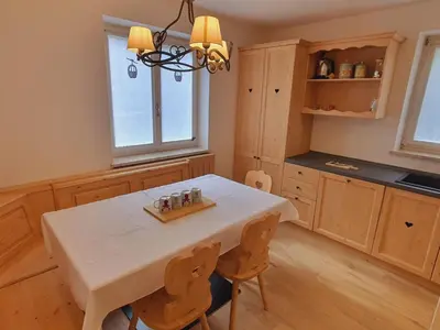 a kitchen with a white table and wooden cabinets at Cuore delle Dolomiti - Alpine Stay Apartments in Ziano di Fiemme