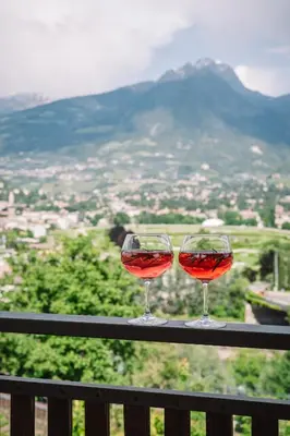 two glasses of red wine sitting on a rail at Ferienappartement Freiblick in Marlengo