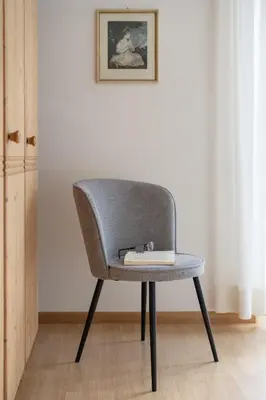 a gray chair sitting in a room with a book at Ferienappartement Freiblick in Marlengo