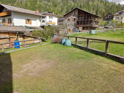 a yard with a fence and houses in the background at Tabia Maredane in Falcade