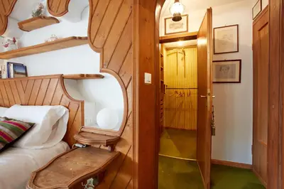 a small bedroom with a bed and a wooden door at Lioda Castle in Cortina dʼAmpezzo