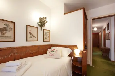 a bedroom with a bed with white sheets and a mirror at Lioda Castle in Cortina dʼAmpezzo