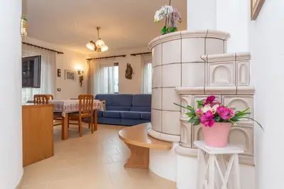 a living room with a blue couch and a table with flowers at Casa Erica in Falcade