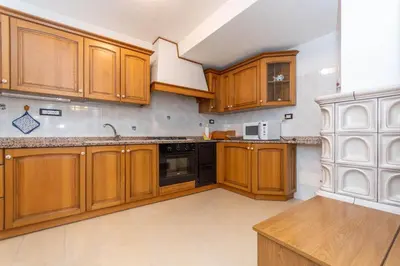 a kitchen with wooden cabinets and black appliances at Casa Erica in Falcade