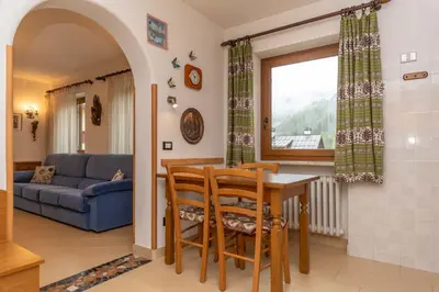 a kitchen and living room with a table and chairs at Casa Erica in Falcade