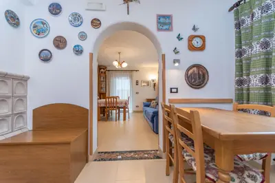 a kitchen and dining room with a table and plates on the wall at Casa Erica in Falcade