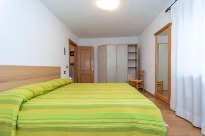 a bedroom with a bed with a yellow and green bedspread at Casa Erica in Falcade