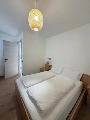 a bedroom with a white bed with a pendant light at Cesa Balzan in Canazei