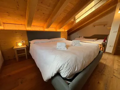 a bedroom with a large bed with white sheets at Arabba - Al Vecio Soler in Livinallongo del Col di Lana