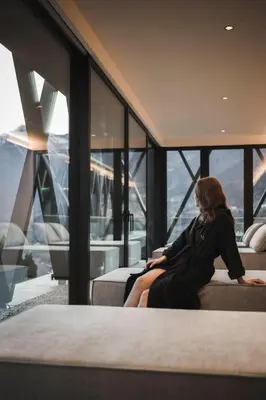 a woman sitting on a bed in a room with windows at SomVita Suites in Tirolo