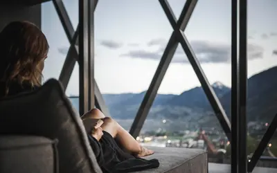 a woman sitting in a chair looking out of a window at SomVita Suites in Tirolo