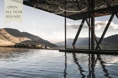 a pool of water with mountains in the background at SomVita Suites in Tirolo