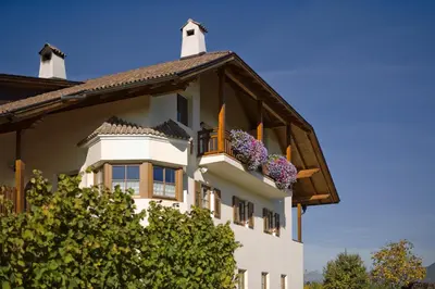 a white house with flowers in a balcony at Ferienwohnungen Plonerhof in San Paolo