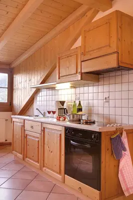 a kitchen with wooden cabinets and a stove top oven at Ferienwohnungen Plonerhof in San Paolo