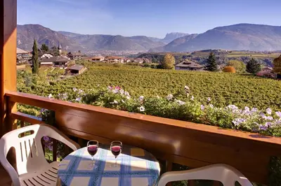 a table and two chairs with wine glasses on a balcony at Ferienwohnungen Plonerhof in San Paolo
