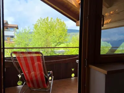 a red chair sitting on a balcony looking out a window at Residence Rastbichl - Apartments & Indoor-Pool in Maranza