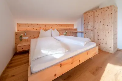 a kitchen and living room with wooden ceilings and a table at Moosbichlerhof in Marlengo