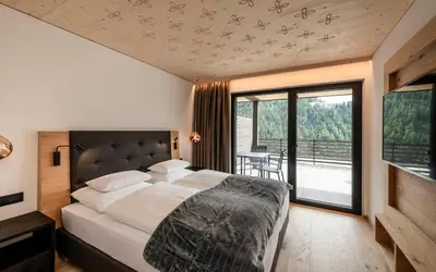 a bedroom with a large bed and a large window at Apartments Aois 4 Elements Suites in La Valle