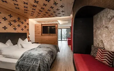 a bedroom with a large bed and a red rug at Apartments Aois 4 Elements Suites in La Valle