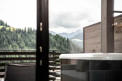 a room with a tub and a view of the mountains at Apartments Aois 4 Elements Suites in La Valle