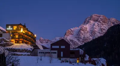 a building in the snow at night with a mountain at Apartments Aois 4 Elements Suites in La Valle