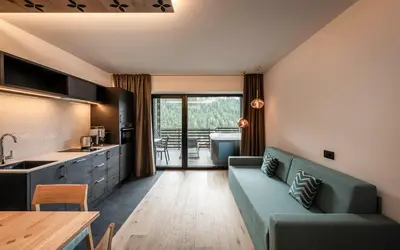 a living room with a blue couch and a kitchen at Apartments Aois 4 Elements Suites in La Valle