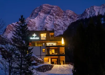 a house in front of a mountain at night at Apartments Aois 4 Elements Suites in La Valle