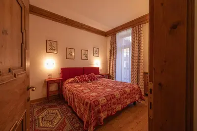 a bedroom with a red bed and a window at Casa Ciclamino, direttamente sul Corso di Cortina dAmpezzo in Cortina dʼAmpezzo