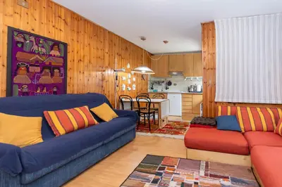 a living room with a blue couch and a kitchen at Casa Ciadenac in Soraga