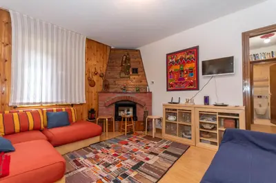 a living room with a red couch and a fireplace at Casa Ciadenac in Soraga
