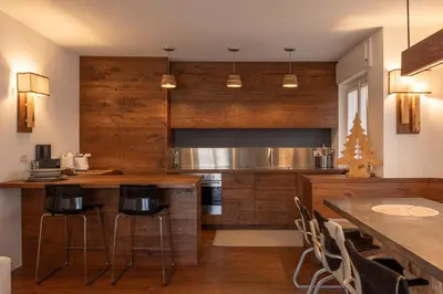 a kitchen with wooden cabinets and a table and chairs at Casa Bucaneve, con terrazza panoramica sulle Dolomiti in Cortina dʼAmpezzo