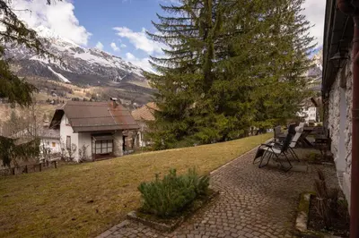 a bench sitting on a sidewalk in front of a house at Casa Bucaneve, con terrazza panoramica sulle Dolomiti in Cortina dʼAmpezzo