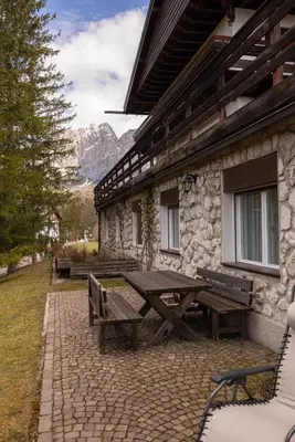 a picnic table and benches outside of a building at Casa Bucaneve, con terrazza panoramica sulle Dolomiti in Cortina dʼAmpezzo