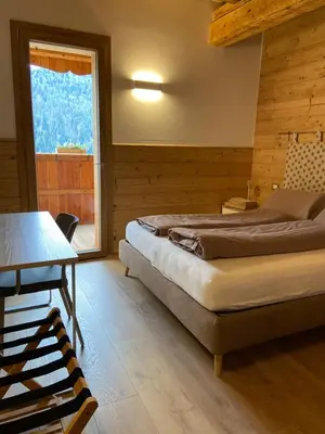 a bedroom with a bed and a table and a window at Tabià del Belli in Livinallongo del Col di Lana