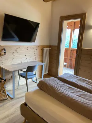 a bedroom with a bed and a desk and a tv at Tabià del Belli in Livinallongo del Col di Lana
