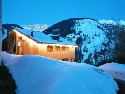 a building covered in snow with mountains in the background at Tabià del Belli in Livinallongo del Col di Lana