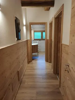 a hallway of a bathroom with wooden floors and a sink at Tabià del Belli in Livinallongo del Col di Lana