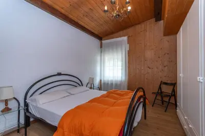 a bedroom with a bed with an orange blanket at Casa Bristol in Pozza di Fassa