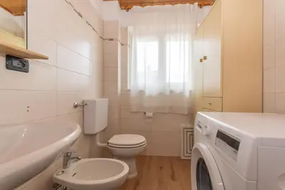 a bathroom with a toilet sink and a washing machine at Casa Bristol in Pozza di Fassa