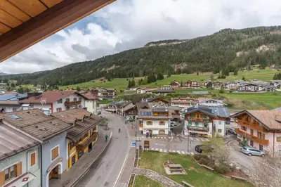 a village in the mountains with a road and houses at Casa Bristol in Pozza di Fassa