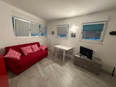 a living room with a red couch and a television at Ida s home free WiFi AC in Bolzano