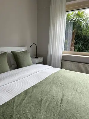 a bedroom with a large white bed with a window at Garden Apartment Villa Corazza in Tirolo
