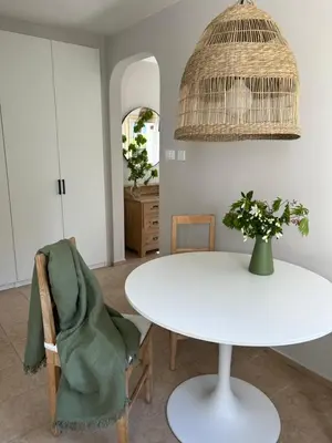 a dining room with a white table and a pendant light at Garden Apartment Villa Corazza in Tirolo